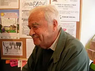 Photo en couleurs d'un homme en buste, de trois quarts profil, à cheveux et moustache blancs