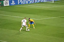 Photo de Karim Benzema en vue plongeante de dos en train de dribbler un joueur de la Juventus Turin en ligue des champions.