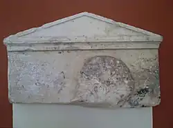 Haut de la stèle à fronton et antéfixes représentant la tête d'un jeune homme (A1026). Marbre de Paros, fin du Ve&nbsp;siècle&nbsp;av. J.-C.