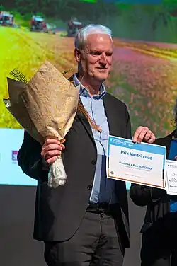 Personne tenant un bouquet de fleurs et une attestation de prix.