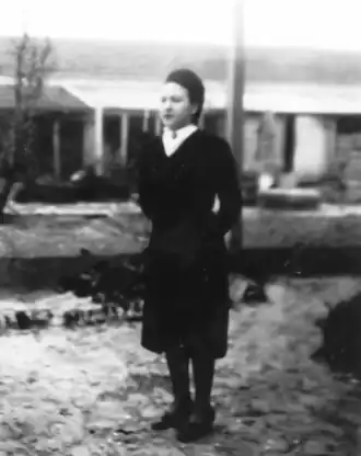 Photo noir et blanc d'une femme debout, de trois quarts face, les mains derrière le dos