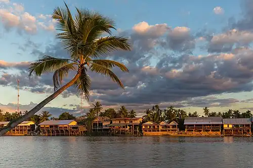 Rive de l'île de Don Khon avec maisons en bois sur pilotis et nuages colorés, depuis Don Det.