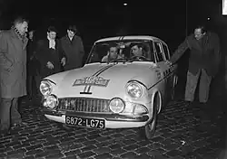 Photographie en noir et blanc montrant deux hommes dans une voiture de course.