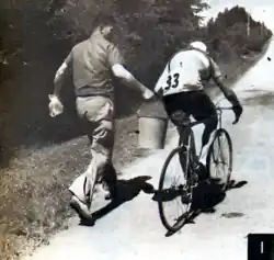 Photo en noir et blanc d'un homme proposant un seau d'eau à un cycliste professionnel.