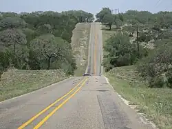 Vue d'une route bordée de verdure et d'arbres.