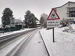 Une route enneigée avec le panonceau verglas fréquent