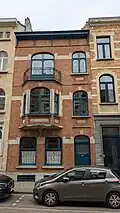Au no 12 : maison de style éclectique teinté d'Art Déco, de trois niveaux de composition asymétrique, construite pour et par les entreprises Caron et Vandiest, 1924. Façade de briques rouges, rehaussée d'éléments enduits en simili-pierre blanche.