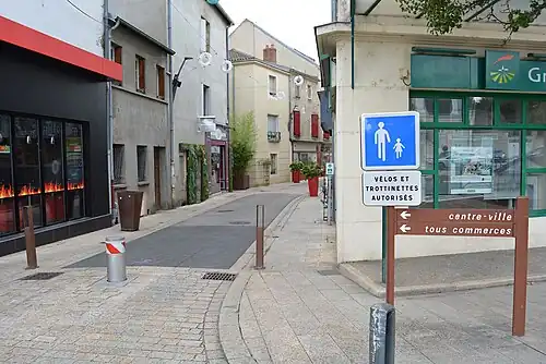 Une rue piétonne accompagnée de deux panneaux, le premier à fond bleu indiquant une entrée d'aire piétonne