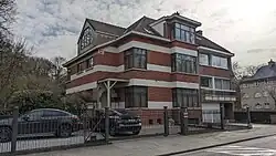 au no&nbsp;2, maison plurifamiliale, à trois habitations, de style moderniste, architecte Léon Smets, 1936. Construction non attenante à gauche, de deux niveaux sous toiture à croupes. Façades en briques, rehaussées d'éléments cimentés. Vers la rue, les trois travées s'avancent en saillies successives. Travée d'accès sur l'angle. La porte, à arc en plein cintre, a été dotée postérieurement d'un auvent à petits-fers. Troisième travée en ressaut, de trois niveaux sur garage. Travée centrale caractérisée par des fenêtres disposées sur l'angle.