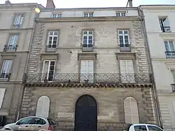 Façade en pierre grise d'un immeuble de trois étages.