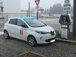 Photographie en couleurs d’une voiture électrique blanche en cours de charge.