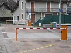 Photographie en couleurs de deux barrières relevables en position fermée à proximité d'une maison.