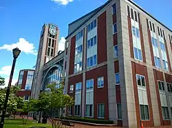 Immeuble de 5 étages en briques rouges à parements blancs, une tour avec une horloge à l'un de ses angles.