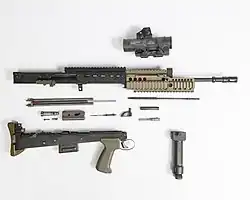 photographie en couleur montrant un fusil d’assaut démonté sur fond blanc à la manière d’un plan éclaté