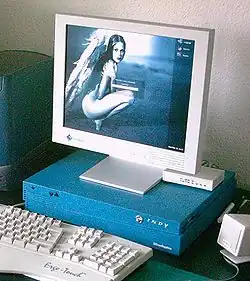 Ordinateur posé sur un bureau, composé d'un moniteur cathodique (affichant une femme accroupie), d'une unité centrale de couleur bleue et d'un clavier d'ordinateur.