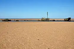 Épave d'un navire au milieu d'une plage de sable.
