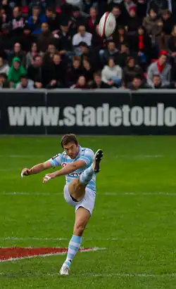 Photo d'un homme de face, venant de frapper un ballon qui se trouve devant lui en l'air.