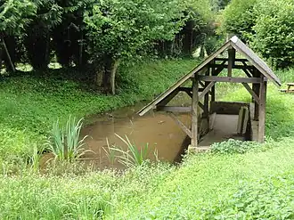 Photographie en couleurs d'un ruisseau longeant un lavoir.