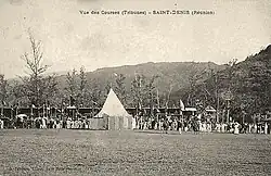 Photographie sépia d'une vaste zone gazonnée et d’une foule indistincte.