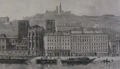 Gravure noir et blanc d’une cathédrale, surplombant un cours d’eau. À l’arrière, une église juchée sur une colline.