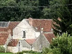 Photographie en couleurs d'un ancien prieuré, le pignon percé d'une baie en plein cintre.