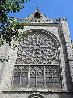 Photographie d'un pignon de transept d'église, avec une rose à remplage rayonnant.
