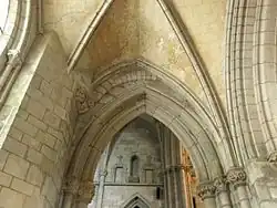 Photographie d'une arcade brisée avec des restes d'une arcade en plein cintre au-dessus.