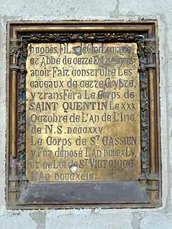 Plaque de bronze gravée et incrustée dans un mur en pierre.