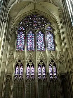 En haut de l'image, grande rosace à quatre branches. En dessous, galerie éclairée par des verrières décoratives.