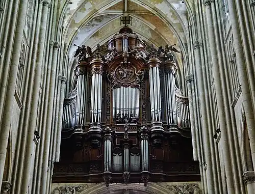 Grand buffet d'orgue en bois, surmonté d'une croix et de quatre statues d'anges dont deux soufflant dans des trompettes.