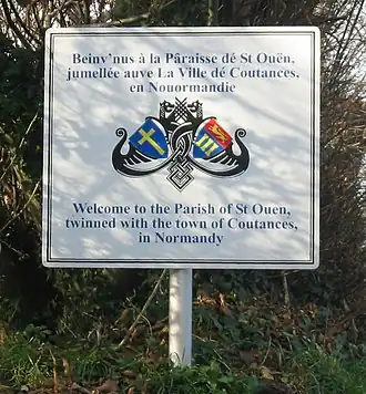 Panneau de jumelage entre les communes de Saint-Ouens et Coutances. En anglais et en jersiais, mais pas en français.