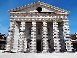 Portique couronné d'un fronton à jour dont le tympan est percé d'un œil-de-bœuf (saline royale d'Arc-et-Senans).