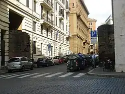 Photographie en couleurs d'une rue passant par la brèche d'une muraille