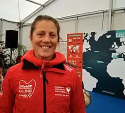 Portrait de face, souriante, en veste de quart rouge.