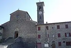 Photographie de la façade d'une église médiévale située dans un village et surmontée d'un campanile