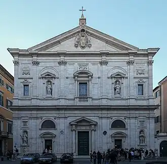 Façade d'un bâtiment en pierre de deux étages, surmonté d'une croix.