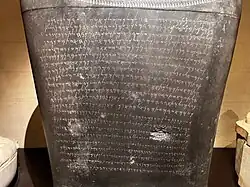 Three quarter view of a large black stone inscribed with 22 lines of Phoenician text.
