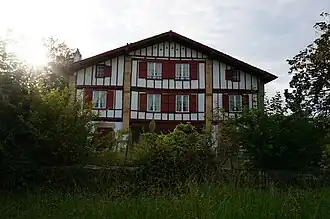 Vue d'une maison à deux étages aux pans de bois rouge.