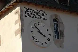 Photographie d’une horloge murale avec une inscription en basque.