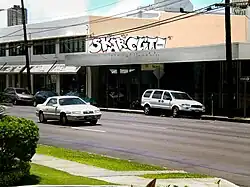 Deux graffitis en blanc sur un mur au-dessus d'un magasin de voitures abandonné.