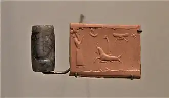 Sceau-cylindre en sardoine sans inscription représentant une scène de culte royal devant des symboles divins. Musée du Louvre.