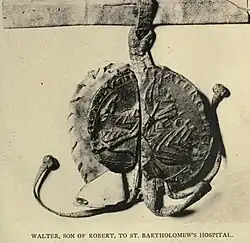 Photographie sombre d'un sceau appendu où on aperçoit des motifs à chevrons