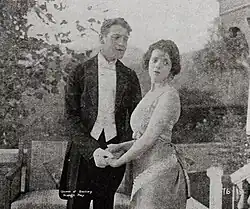 Photo en noir et blanc représentant un homme en costume noir et une femme en robe claire