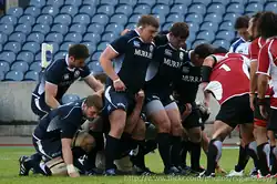 gros plan sur un côté de la mêlée avant la formation de celle-ci. Le pilier est debout, soudé au talonneur, les postes 4 à 7 sont en place, accroupis, le n.8 est debout détaché.