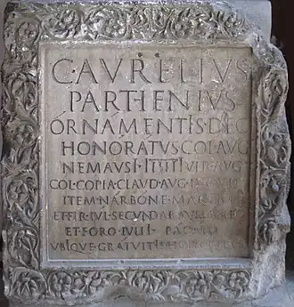 Le H dimidié à droite dans le mot PARTꟵENIUS, «&nbsp;Parthenius » sur la deuxième ligne d’une inscription épigraphique du Musée Archéologique de Nîmes.