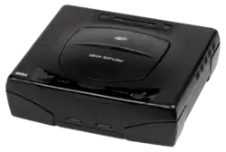 Photo d'une Saturn noir ; elle dispose d'un capot pouvant accueillir un CD et deux prises sur le devant pour brancher deux manettes