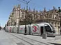 Une rame Urbos III passe devant la cathédrale, pantographe replié.