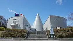Photographie couleur d'un bâtiment moderne avec des drapeaux flottants au vent.