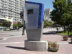 Panneau portant les anneaux olympiques sur une place piétonne.