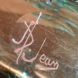 Signature d'Auguste Jean, A. Jean. Émail rouge-brun sur verre. Entre 1877 et 1884.